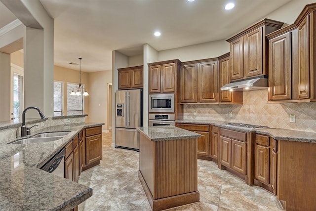 kitchen with sink, appliances with stainless steel finishes, hanging light fixtures, a kitchen island, and stone countertops