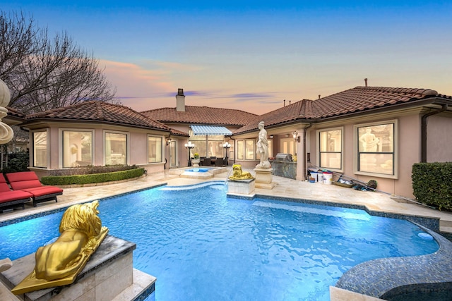 pool at dusk featuring a patio and an in ground hot tub