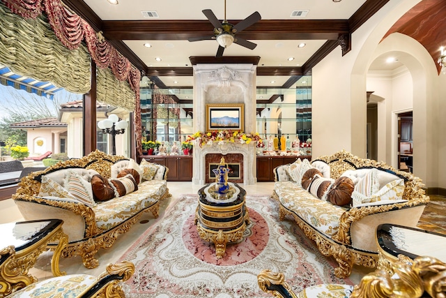 living room featuring beamed ceiling, ornamental molding, a high end fireplace, and ceiling fan