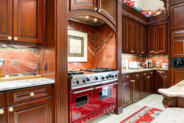 kitchen featuring range with two ovens, tasteful backsplash, light stone countertops, and light tile patterned floors