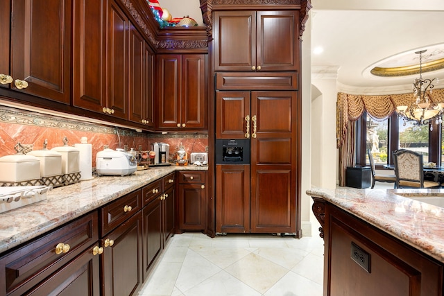 kitchen with light stone counters, a notable chandelier, decorative backsplash, and hanging light fixtures