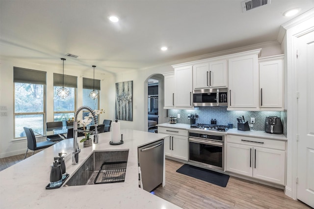 kitchen with white cabinetry, stainless steel appliances, light stone countertops, and sink