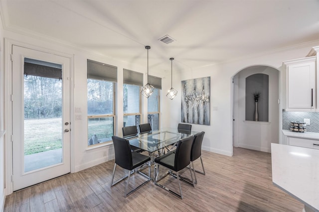 dining area with ornamental molding and light hardwood / wood-style flooring