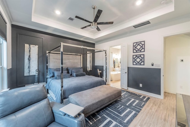 bedroom with a tray ceiling, ornamental molding, and light wood-type flooring