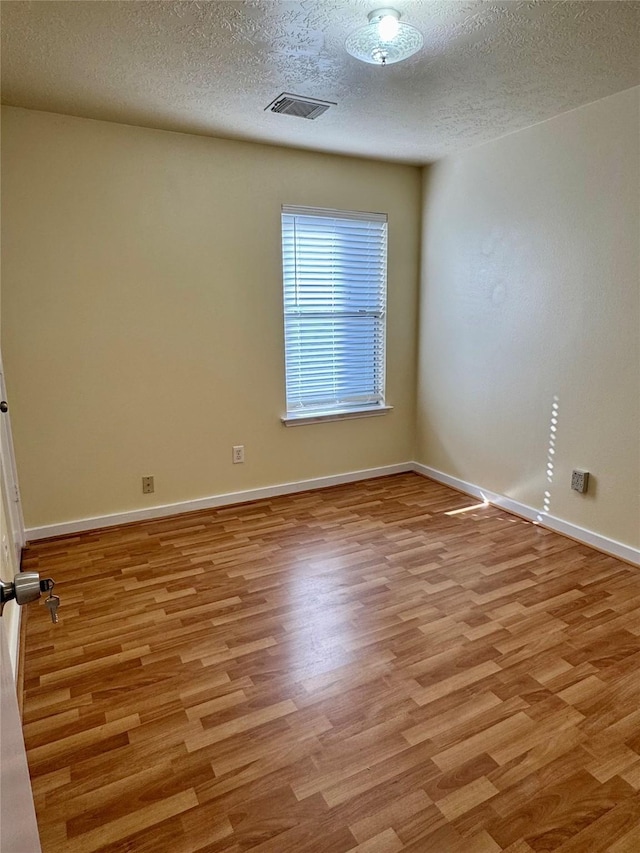 unfurnished room featuring a textured ceiling and light hardwood / wood-style flooring