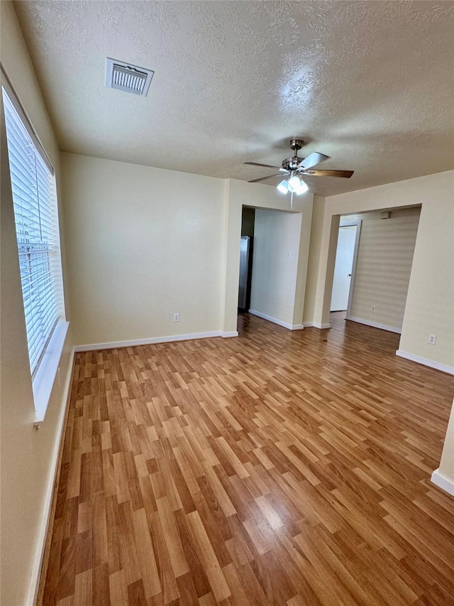 empty room featuring ceiling fan, a textured ceiling, and light wood-type flooring