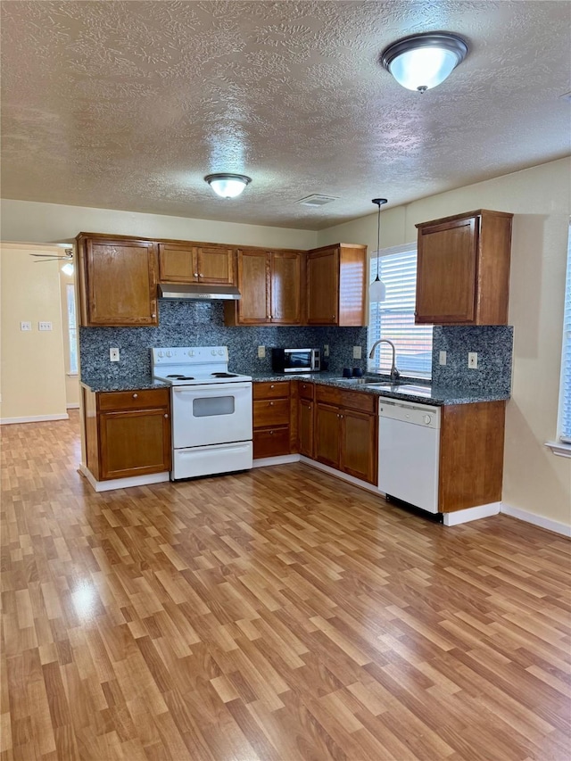 kitchen with sink, decorative light fixtures, light hardwood / wood-style flooring, white appliances, and backsplash