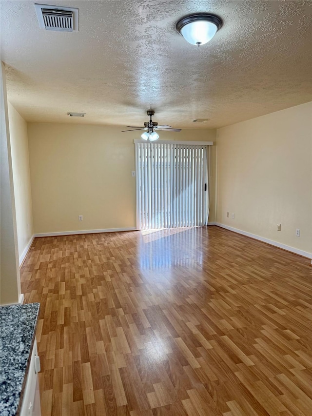 spare room featuring ceiling fan, light hardwood / wood-style floors, and a textured ceiling