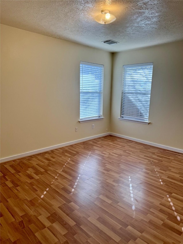 unfurnished room featuring light hardwood / wood-style floors and a textured ceiling