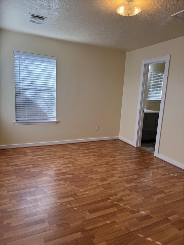 unfurnished room featuring wood-type flooring and a textured ceiling