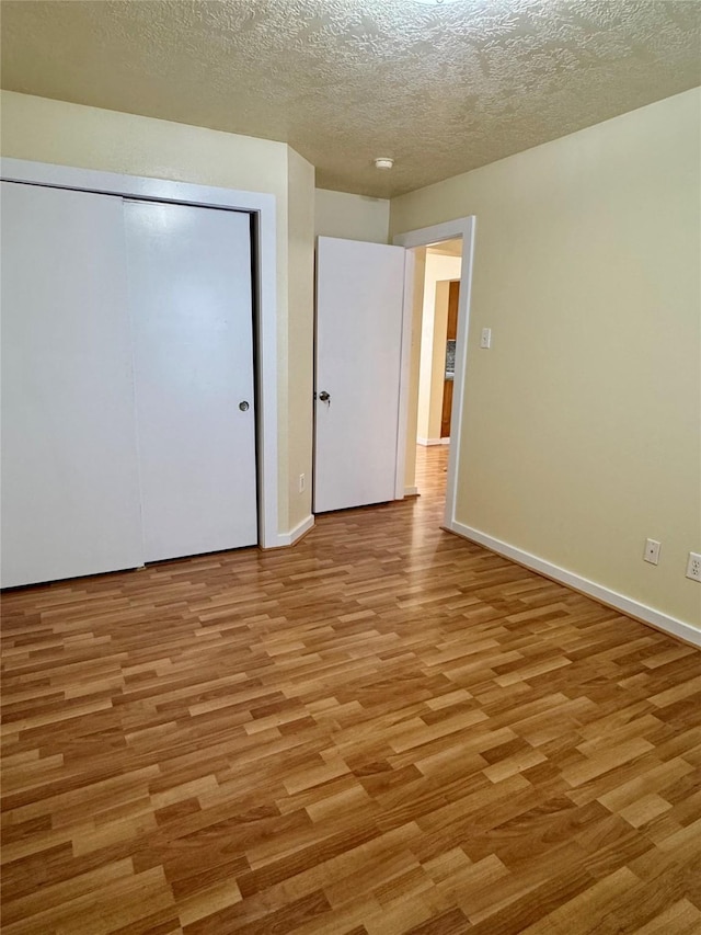 unfurnished bedroom with light hardwood / wood-style flooring, a closet, and a textured ceiling