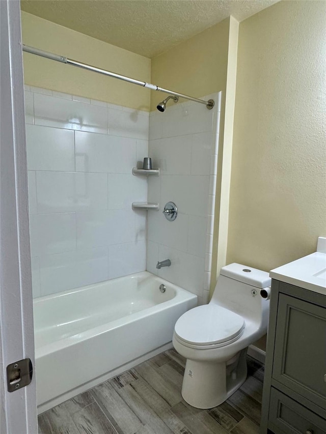 full bathroom featuring toilet, a textured ceiling, vanity, tiled shower / bath combo, and hardwood / wood-style floors