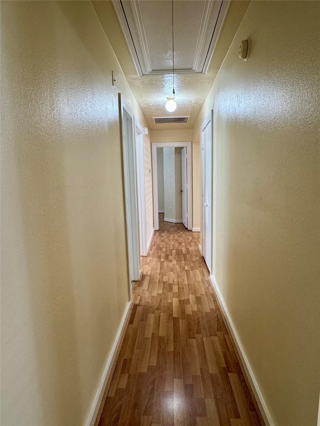 hall with hardwood / wood-style floors and a textured ceiling