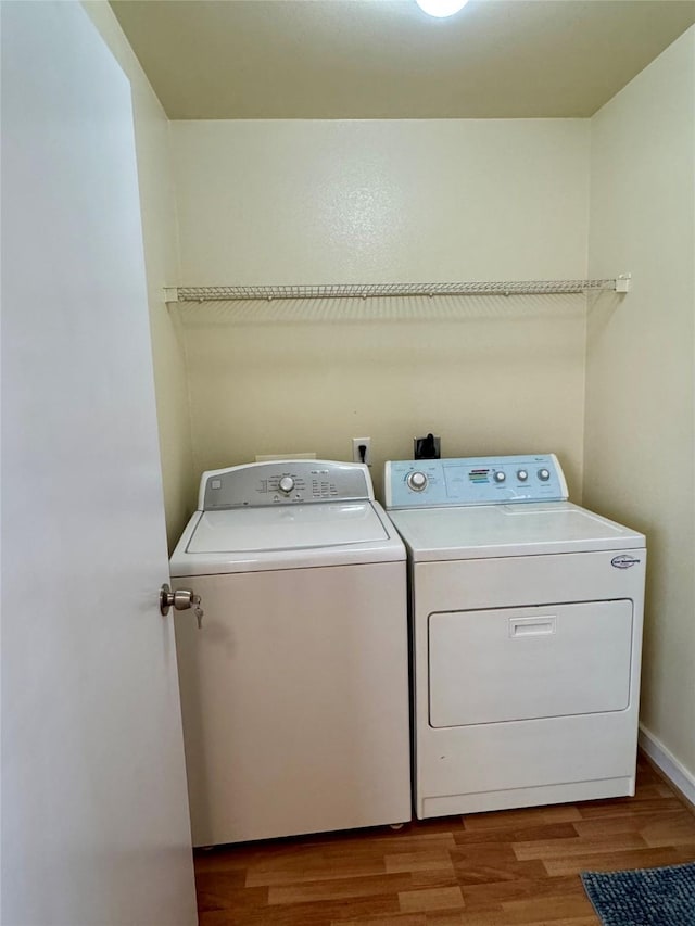 laundry room featuring washing machine and clothes dryer and hardwood / wood-style floors