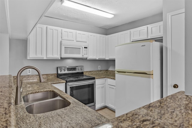 kitchen featuring sink, dark stone countertops, white cabinets, and white appliances