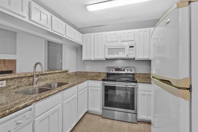 kitchen featuring dark stone countertops, white appliances, and white cabinets