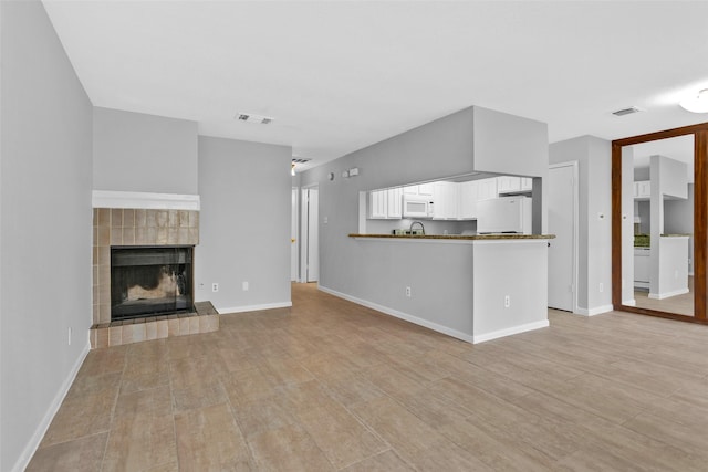 unfurnished living room with a tiled fireplace and light hardwood / wood-style flooring