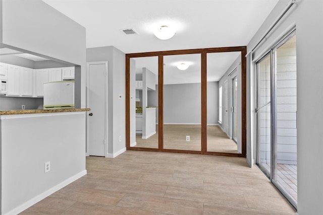 kitchen with fridge, white cabinets, and light hardwood / wood-style flooring