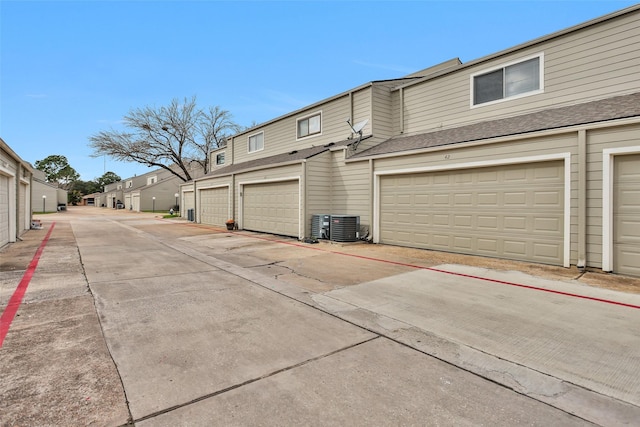 view of side of home with a garage and central air condition unit