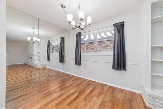 unfurnished dining area featuring an inviting chandelier and wood-type flooring