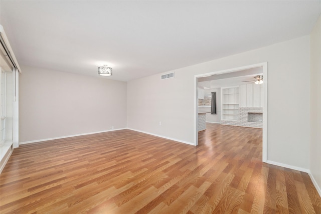 spare room featuring built in features and light hardwood / wood-style floors