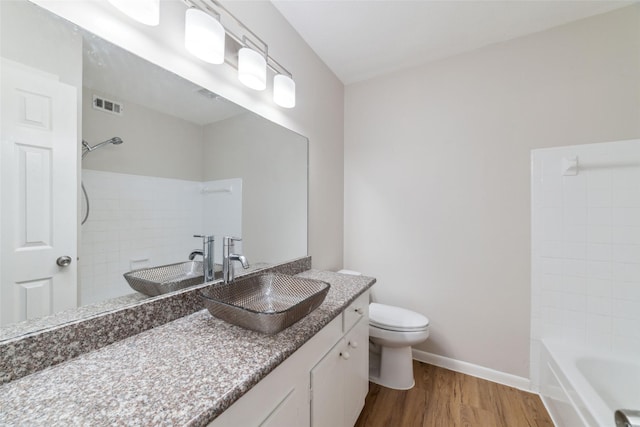 full bathroom featuring vanity, hardwood / wood-style floors, tiled shower / bath combo, and toilet