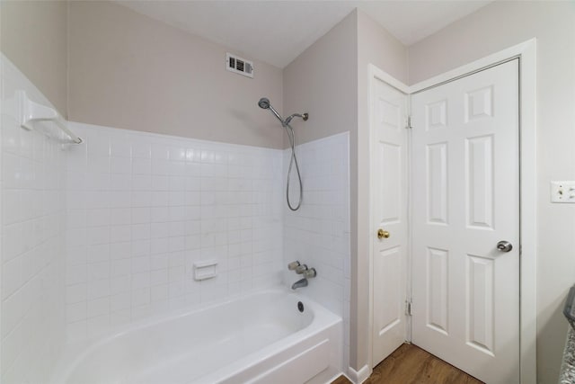 bathroom with tiled shower / bath combo and hardwood / wood-style floors