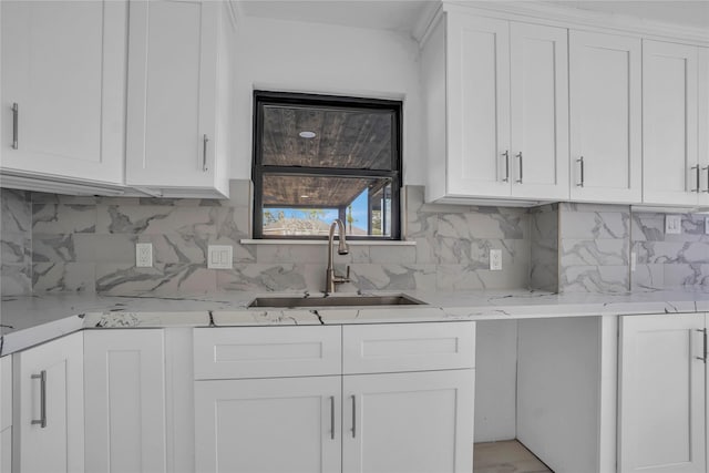 kitchen with white cabinetry, tasteful backsplash, sink, and light stone counters