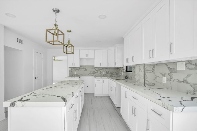 kitchen featuring sink, hanging light fixtures, light stone counters, white cabinets, and a kitchen island