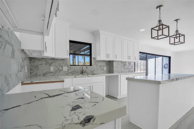 kitchen featuring sink, decorative light fixtures, a kitchen island, white cabinets, and backsplash