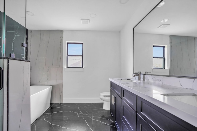 bathroom featuring vanity, a tub to relax in, plenty of natural light, and toilet