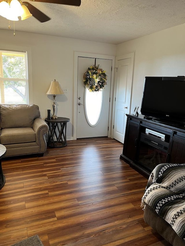 living room with ceiling fan, dark hardwood / wood-style floors, and a textured ceiling