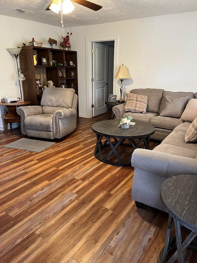 living room featuring hardwood / wood-style flooring, ceiling fan, and a textured ceiling