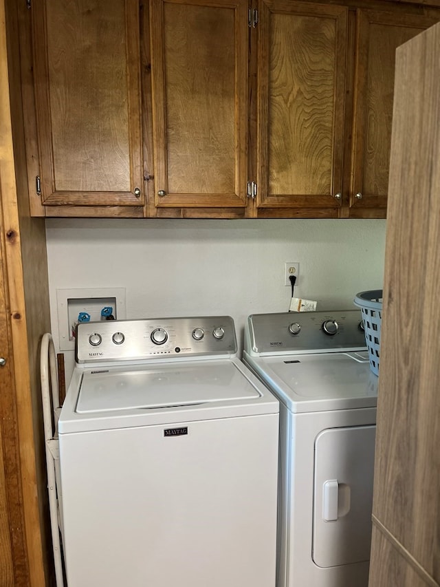 clothes washing area featuring cabinets and washer and clothes dryer