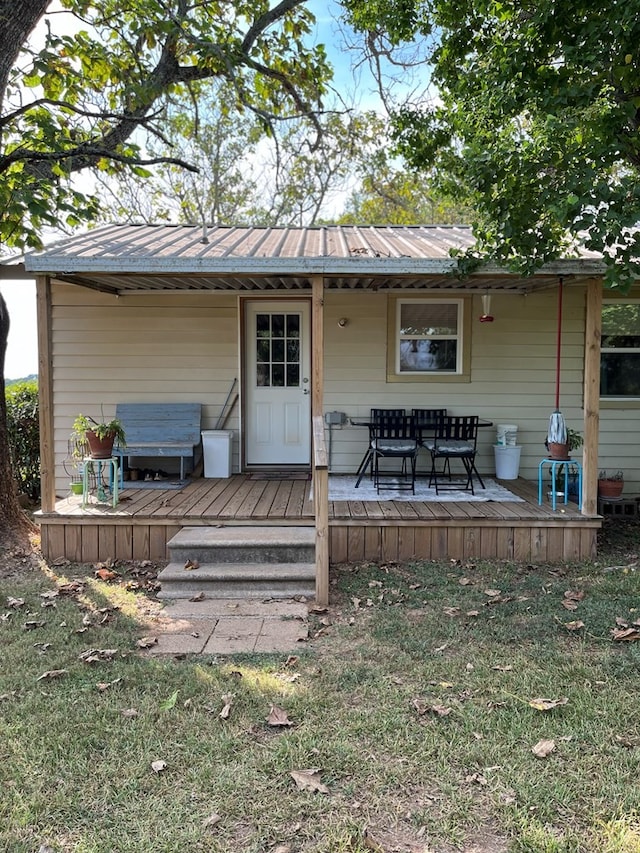 rear view of property with a wooden deck and a lawn