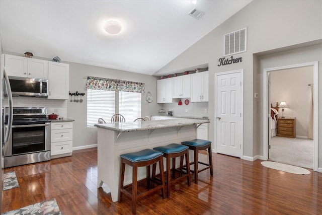 kitchen with a center island, appliances with stainless steel finishes, light stone countertops, and white cabinets