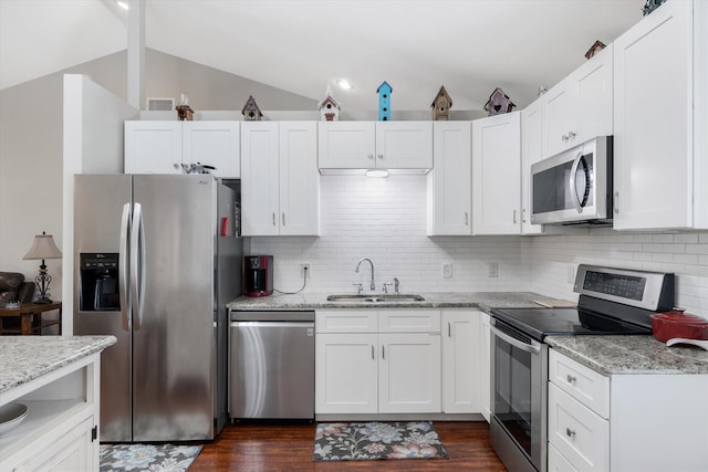 kitchen with tasteful backsplash, white cabinetry, lofted ceiling, sink, and stainless steel appliances