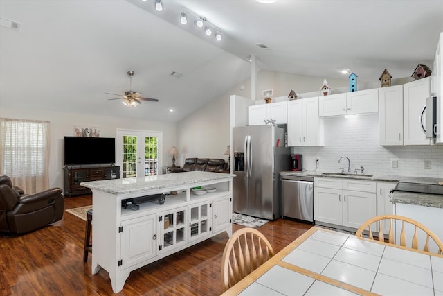 kitchen with lofted ceiling, sink, a breakfast bar area, stainless steel appliances, and white cabinets