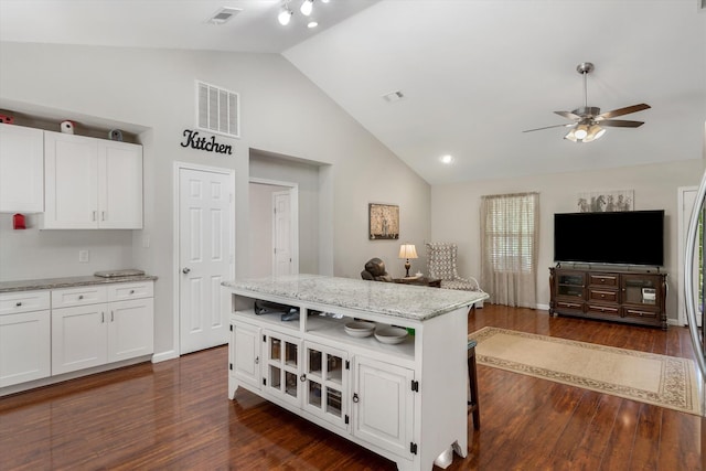 kitchen featuring white cabinetry, a center island, a breakfast bar, and light stone counters