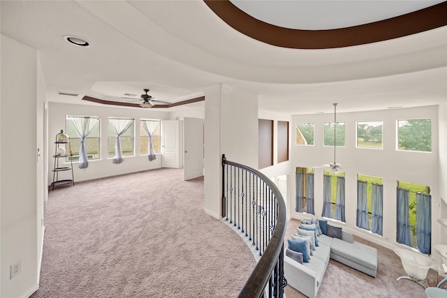 corridor featuring a tray ceiling, a healthy amount of sunlight, carpet flooring, and baseboards