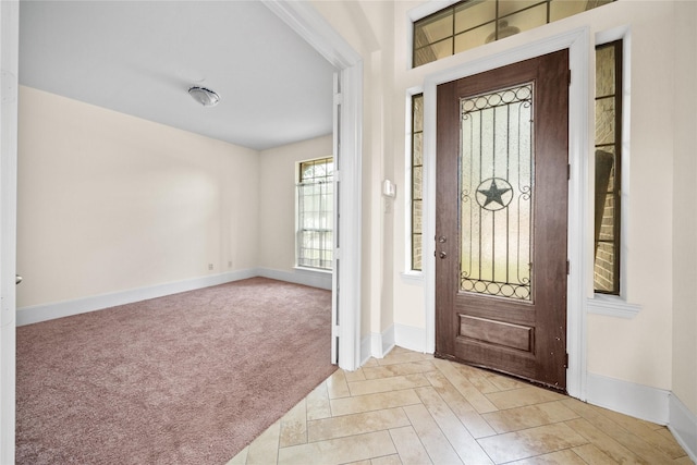 entryway featuring light carpet and baseboards