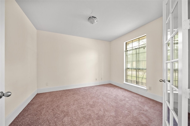 carpeted empty room featuring baseboards