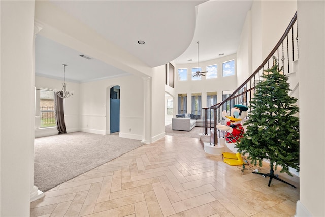 entrance foyer with plenty of natural light, stairs, baseboards, and ceiling fan with notable chandelier