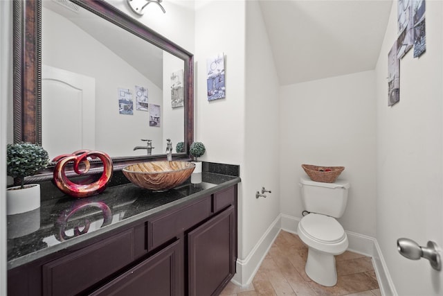 bathroom with lofted ceiling, baseboards, vanity, and toilet