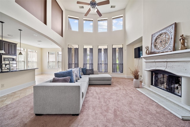 carpeted living area featuring plenty of natural light, a glass covered fireplace, and baseboards