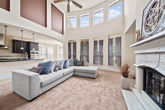 living room featuring baseboards, a fireplace, a wealth of natural light, and light colored carpet