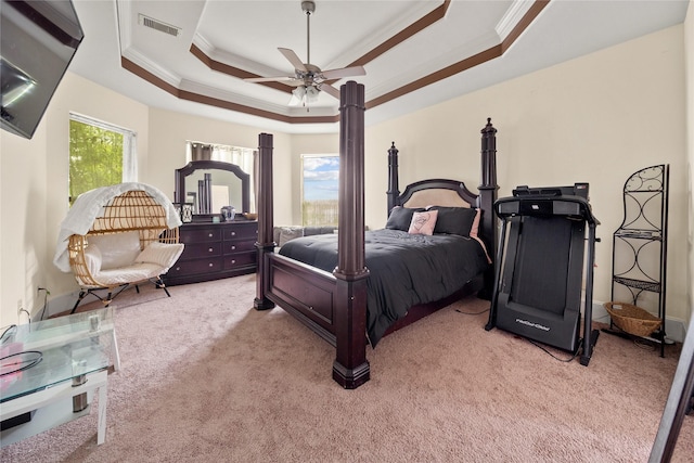 bedroom featuring ceiling fan, light carpet, visible vents, ornamental molding, and a raised ceiling