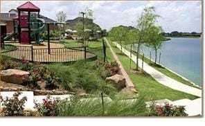 exterior space with playground community, a water view, and fence