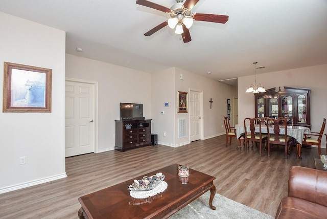 living room with wood-type flooring and ceiling fan with notable chandelier