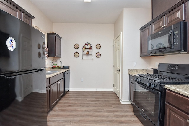 kitchen with dark brown cabinets, light hardwood / wood-style floors, and black appliances